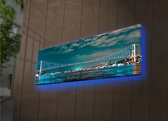 Lerretsbilde med LED belysning 30x90 cm Bro over et rolig vann med bylys i bakgrunnen Mørk blå / Turkis / Lys grønn