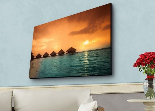 Lerretsbilde med LED belysning Solnedgang over en tropisk strand med bungalower over vannet Oransje / Turkis