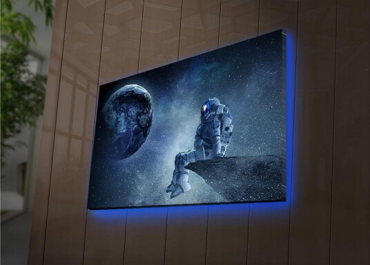 Lerretsbilde med LED belysning 45x70 cm Astronaut sitter på en stein og ser ut på jorden i rommet Mørk blå / Grå / Hvit