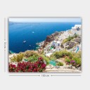 Lerretsbilde 70x100 cm Vakker utsikt over Santorini med hvite hus og blomster som pryder klippene ved havet Blå / Hvit / Grønn