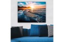 Lerretsbilde 70x100 cm Solnedgang over en strand med milde bølger som ruller inn mot kysten Blå / Oransje / Turkis