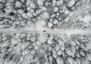 Red Car Driving Through Snowy Forest Plakat Plakat / 100x150cm